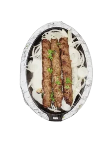 A tray of delicious three pieces of beef seekh kebab atop caramelized onions.