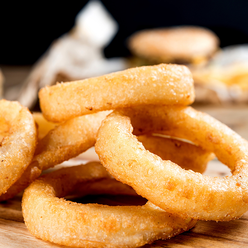 A stack of five crispy, deep-fried onion rings, arranged one on top of the other.
