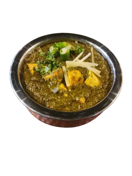 Creamy dish of Palak Paneer in a steel bowl, topped with chili peppers, ginger, and fresh coriander.