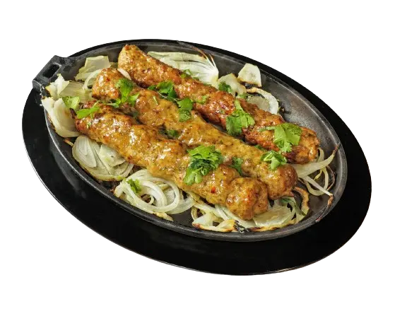 A tray of three delicious pieces of chicken seekh kebab is placed on a bed of caramelized onions.
